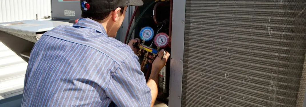 HVAC technician servicing a condenser unit in Nashua